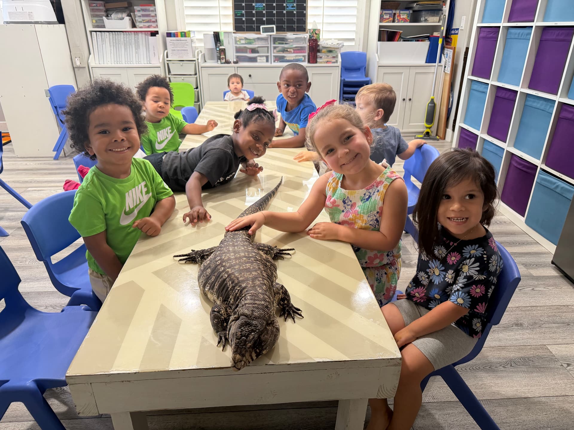 A classroom of smiling children meeting a tegu