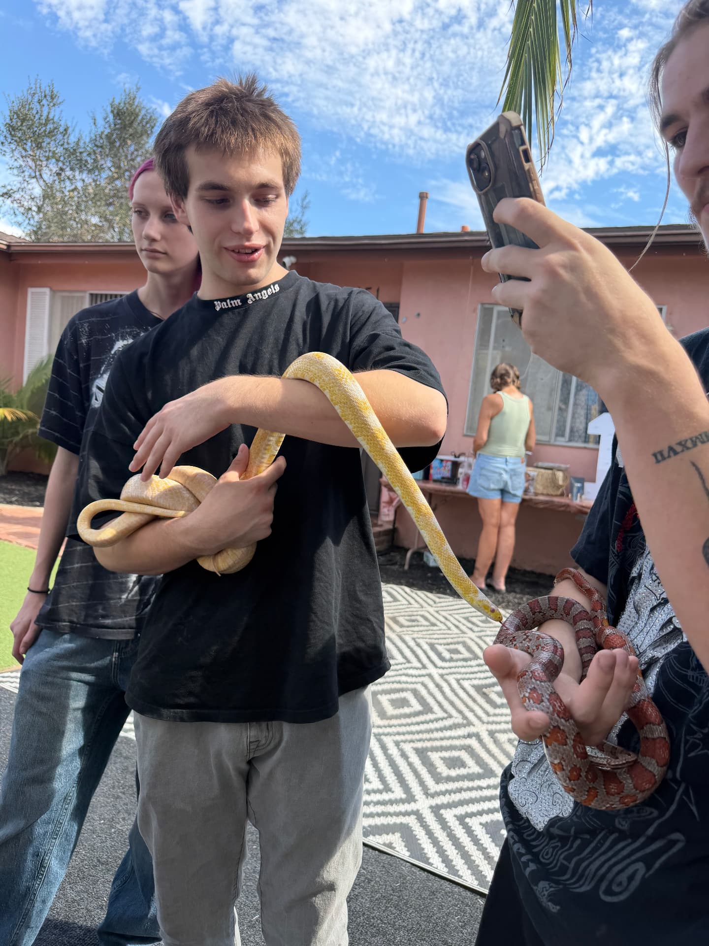 Teen guest holding a snake while a friend takes a photo